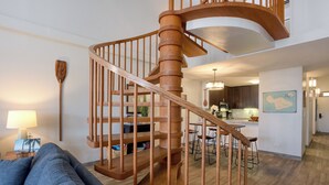 Una escalera espiral de madera en un salón moderno con un sofá y una lámpara.