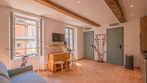 A cozy room with a wooden desk, a television, and a seating area with a sofa and chairs. - IN THE HEART OF THE TOWN CENTRE – STUDIO – CLOSE TO THE BEACH (STE MAXIME)