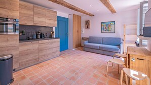 A modern kitchen with wooden cabinets, a blue door, and a tiled floor. - IN THE HEART OF THE TOWN CENTRE – STUDIO – CLOSE TO THE BEACH (STE MAXIME)