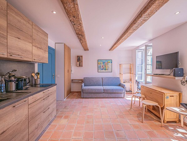 Une cuisine moderne avec des meubles en bois, une porte bleue et un sol carrelé.