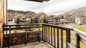 A wooden balcony with a view of a mountainous town.