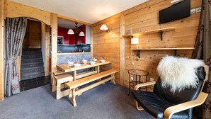 Un intérieur en bois comprenant un coin repas, un canapé et un téléviseur fixé au mur.