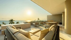 A modern outdoor lounge area with a view of the ocean and palm trees.