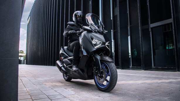 A motorcycle parked in front of a modern building with vertical lines.