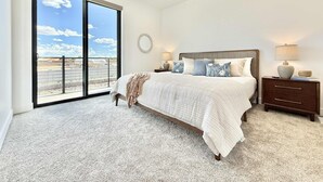 A spacious bedroom with a large bed, a ceiling fan, and a view through a sliding door to an outdoor area. - Stylish 3BR Oasis | Pools, Stargazing + Zion/Bryce (Kanab)