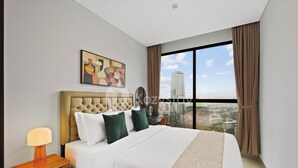 Habitación de hotel moderna con una cama grande, una mesita de noche, una lámpara y vistas a la ciudad a través de la ventana.