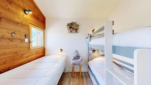 A cozy cabin-style room with wooden walls, a window, bunk beds, and a small table with a lamp. - Cheval Blanc 32 - Crève Coeur (LES AVANCHERS VALMOREL)