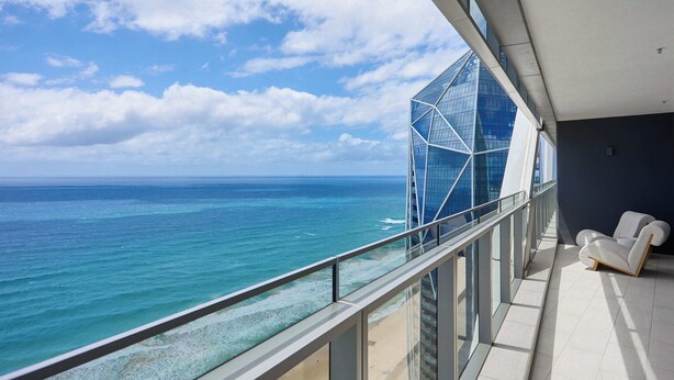 Een balkon met uitzicht op de oceaan en een modern gebouw.