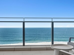 A balcony with a clear view of the ocean, a white table, and a chair. - Jewel Realty (SURFERS PARADISE)