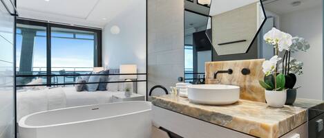 A modern bathroom with a freestanding bathtub, a marble countertop, and a large mirror.