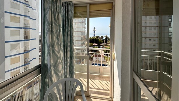 Ein Balkon mit Blick auf ein Gebäude, das einen Leuchtturm, einen Pool und einen klaren Himmel zeigt.