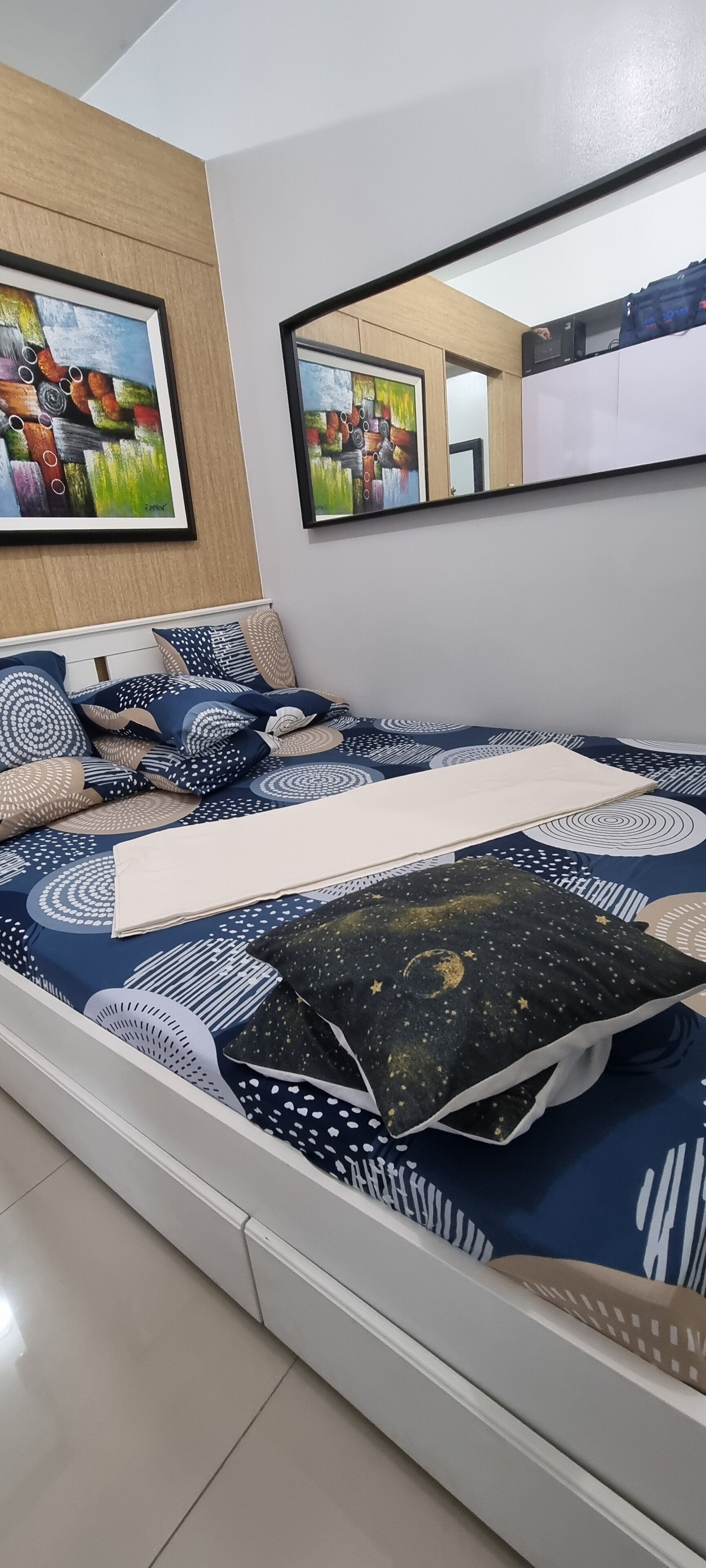 Een moderne slaapkamer met een bed, kussens en twee ingelijste kunstwerken aan de muur.