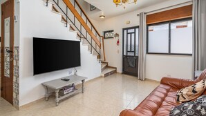Olohuone, jossa on televisio, portaikko, nahkasohva ja kattokruunu.