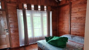 Una stanza in legno con un letto, una finestra con tende e una porta.