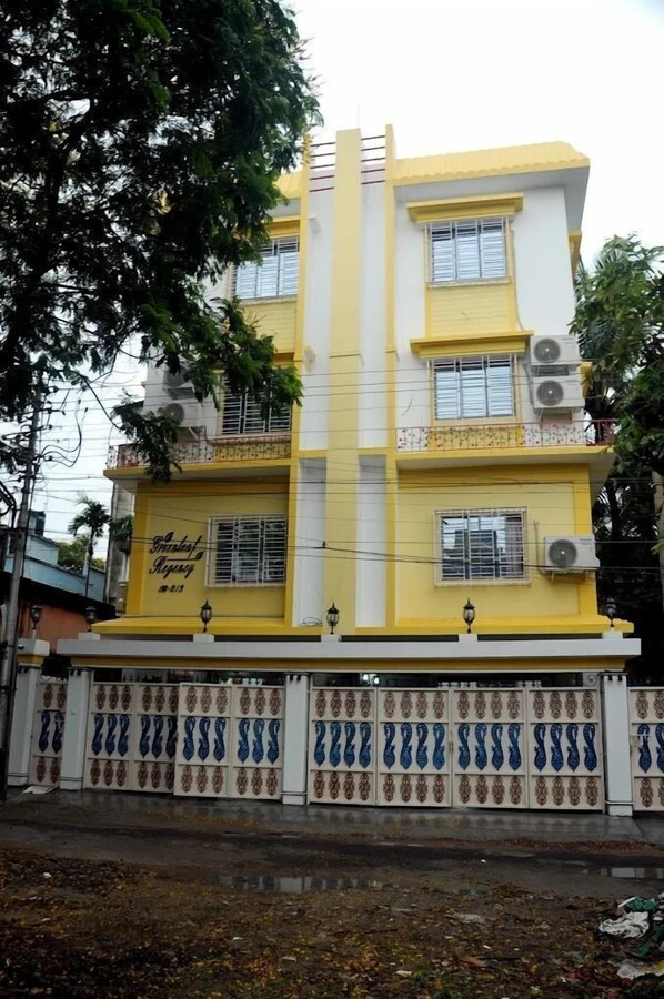 Un bâtiment à deux étages, doté d’une façade jaune et blanche, de nombreuses fenêtres et de climatiseurs.
