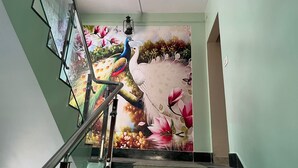 A staircase with a mural featuring birds and flowers. - Green Leaf Regency  (Kolkata)