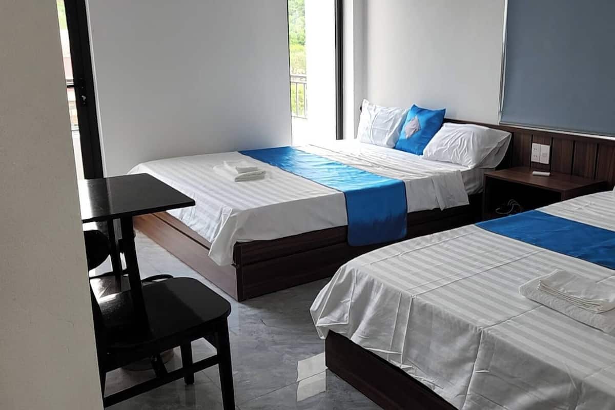 Habitación de hotel con dos camas, un escritorio y una silla.