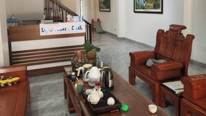 A spacious living area with a wooden coffee table, two wooden chairs, a sofa, and a staircase leading to an upper level. - Loc Phat Hotel MC - by BAY LUXURY (Moc Son)