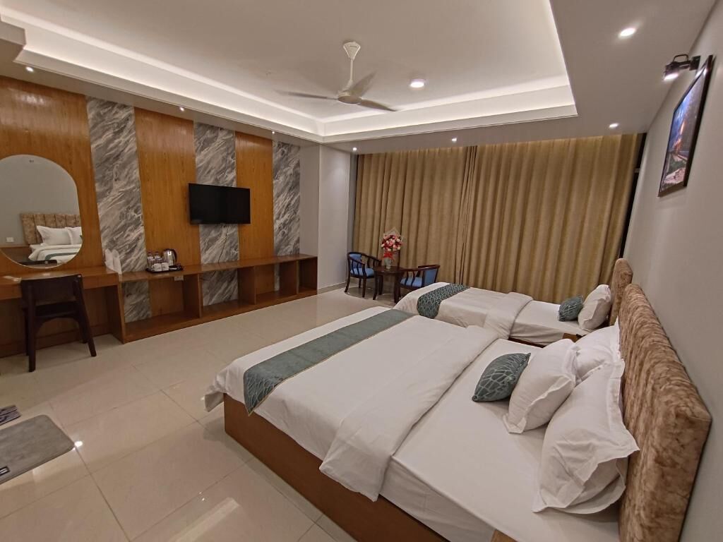 A hotel room with a large bed, a desk, a chair, a television, and a ceiling fan.