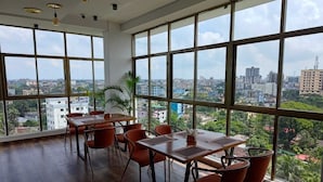 A spacious room with large windows, wooden flooring, and orange chairs. - Sylhet Paradise Inn (Sylhet)