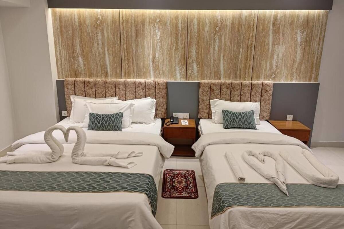 Une chambre d’hôtel avec deux lits, un grand panneau mural et une décoration originale réalisée avec des serviettes en forme de cygne.