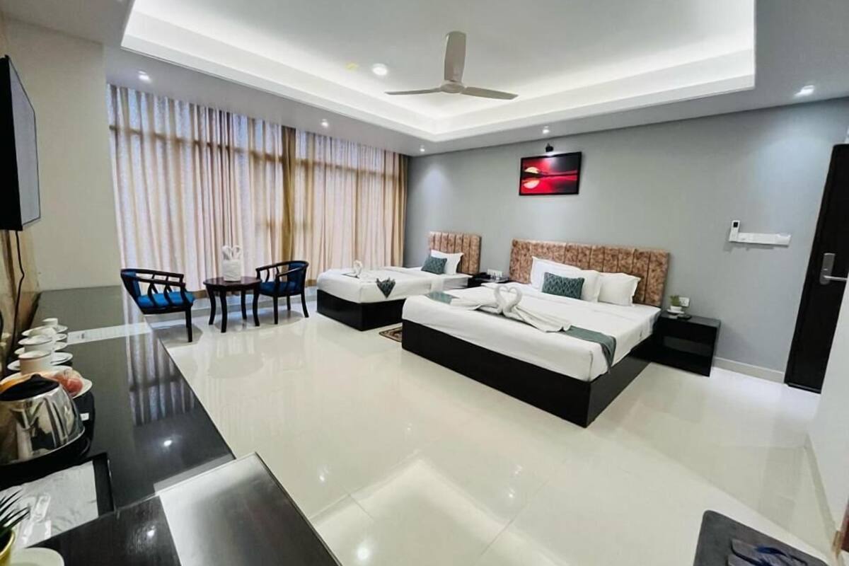 Une chambre d’hôtel moderne dotée d’un grand lit, d’un bureau avec une chaise, d’un ventilateur de plafond et d’un téléviseur fixé au mur.