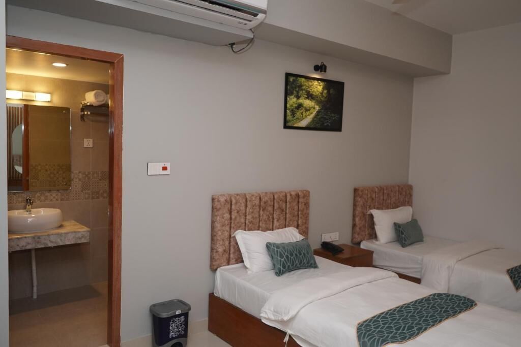 Habitació d'hotel amb dos llits, un bany amb un lavabo i un quadre a la paret.