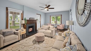 A living room with a fireplace, sofas, a ceiling fan, and large windows. - Charming 3-bedroom house with WiFi, AC in wonderful Toledo (Toledo)