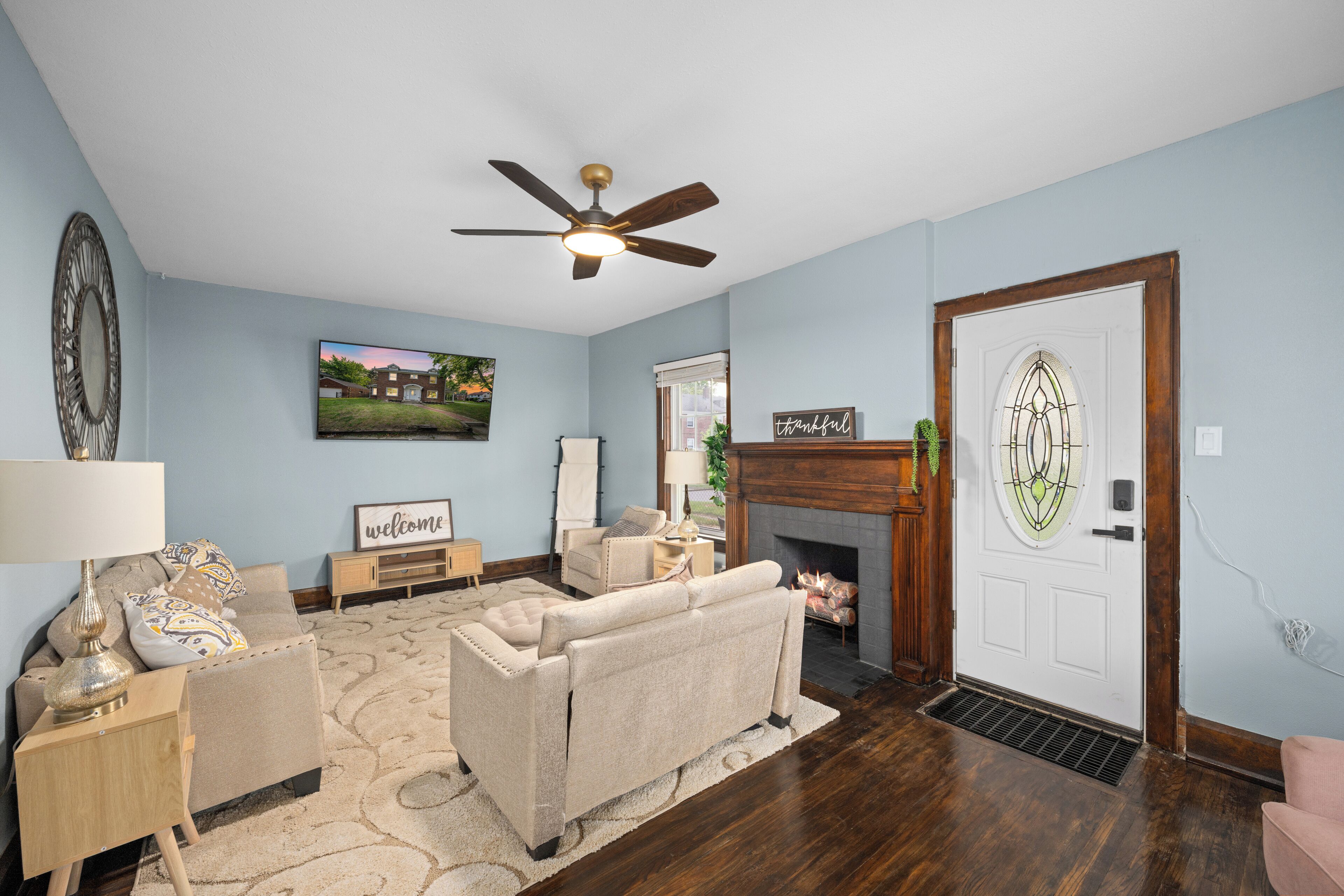 A living room with a fireplace, a ceiling fan, a sofa, a coffee table, and a television.