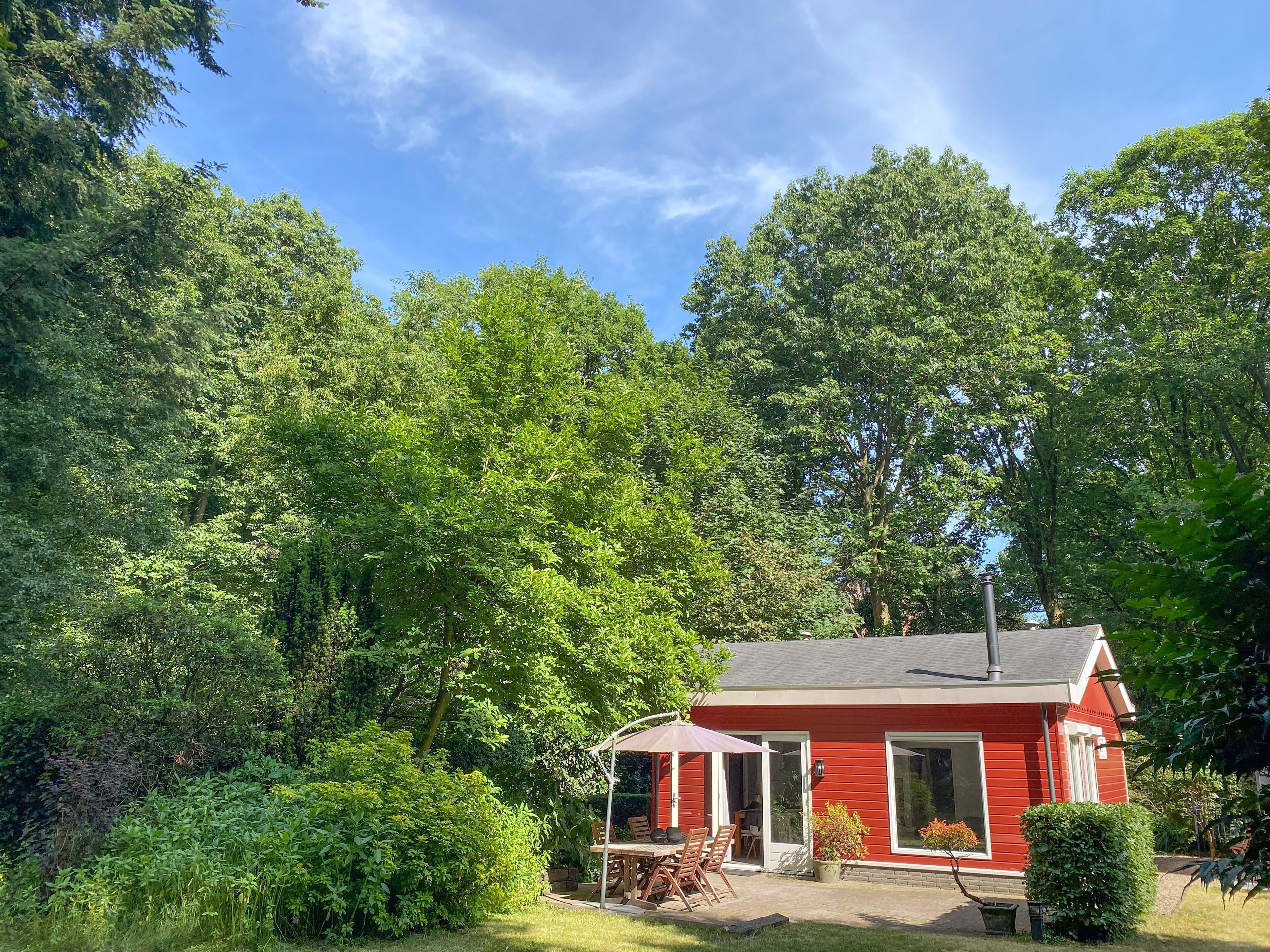 Ein rotes Haus mit überdachter Terrasse und Garten.