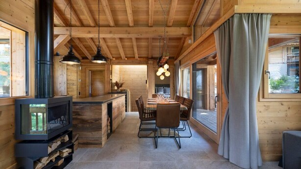 Interior acogedor de una cabaña con comedor, paredes de madera y chimenea.