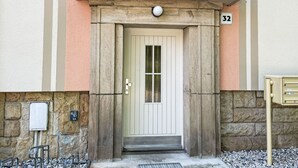 A building entrance with a white door, a mailbox, and a stone wall.
