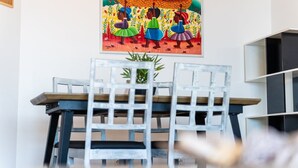 A dining area with a table and chairs, a painting on the wall, and a potted plant. - GuestReady - Caniço city view (Caniço)