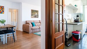 A living room with a sofa, a dining table, chairs, and a painting on the wall. - GuestReady - Caniço city view (Caniço)