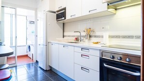 A modern kitchen with white cabinets, a built-in oven, and a microwave. - GuestReady - Caniço city view (Caniço)