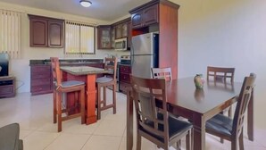 Una cocina con armarios de madera, una mesa de comedor con sillas y un refrigerador.