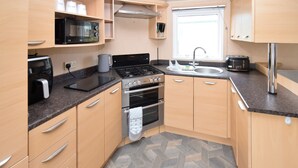 Une cuisine compacte équipée d’un four à micro-ondes, d’une cuisinière, d’un four, d’un évier et d’un grille-pain.