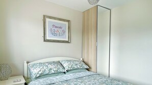 A bedroom with a bed, a nightstand, a framed picture on the wall, and a wardrobe. - 2 bedroom accommodation in Bottesford (Bottesford)