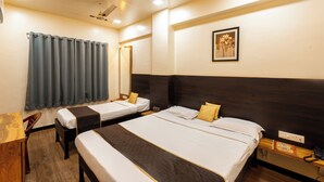 A hotel room with two single beds, a desk, a chair, a mirror, and a ceiling fan. - Hotel Ellora Park (Pune)