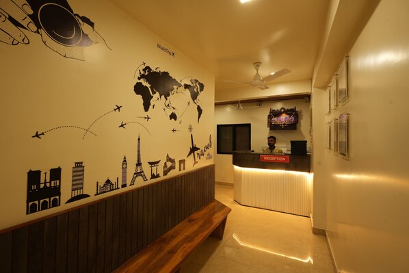 A reception area with a world map mural, a reception desk, a ceiling fan, and a bench. - Hotel Ellora Park (Pune)
