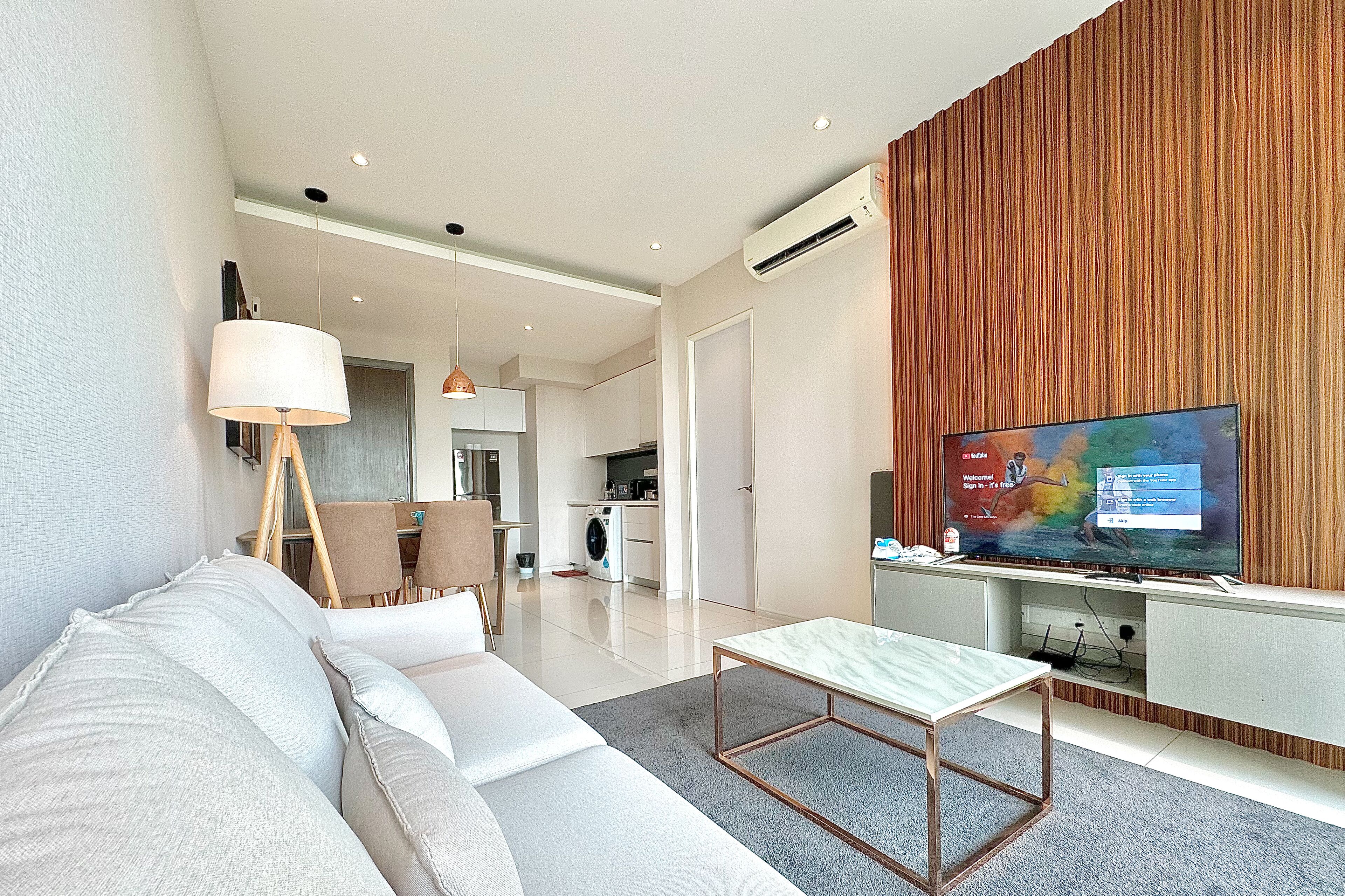 A modern living room with a sofa, a coffee table, and a TV on a wooden accent wall.