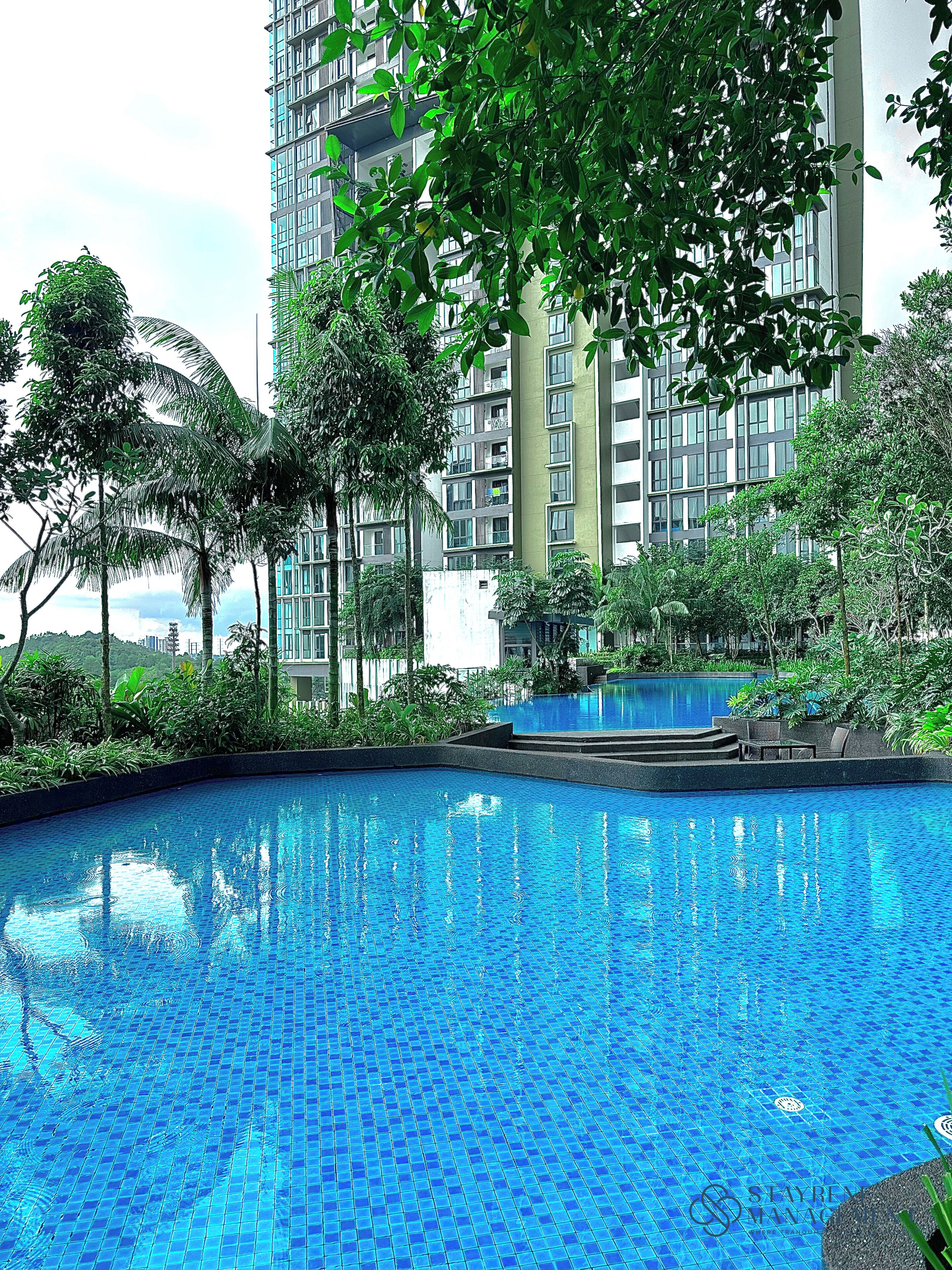 A swimming pool surrounded by lush greenery and tall buildings.