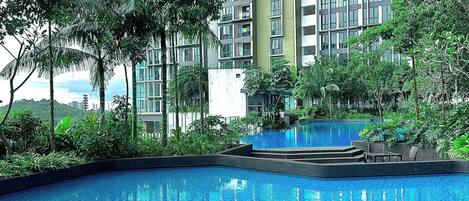 A swimming pool surrounded by lush greenery and tall buildings.