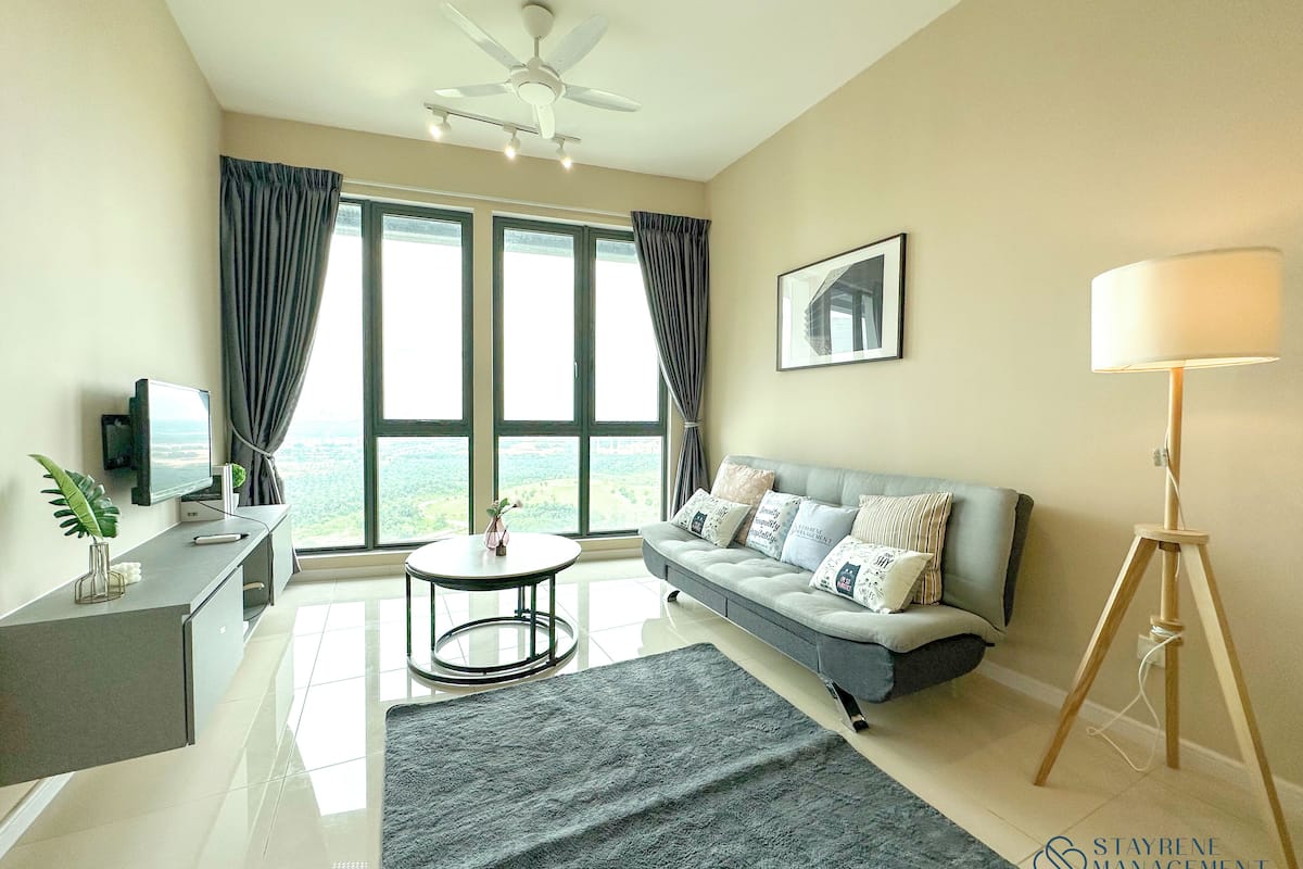 A modern living room with a sofa, a coffee table, a TV, and a large window with curtains.