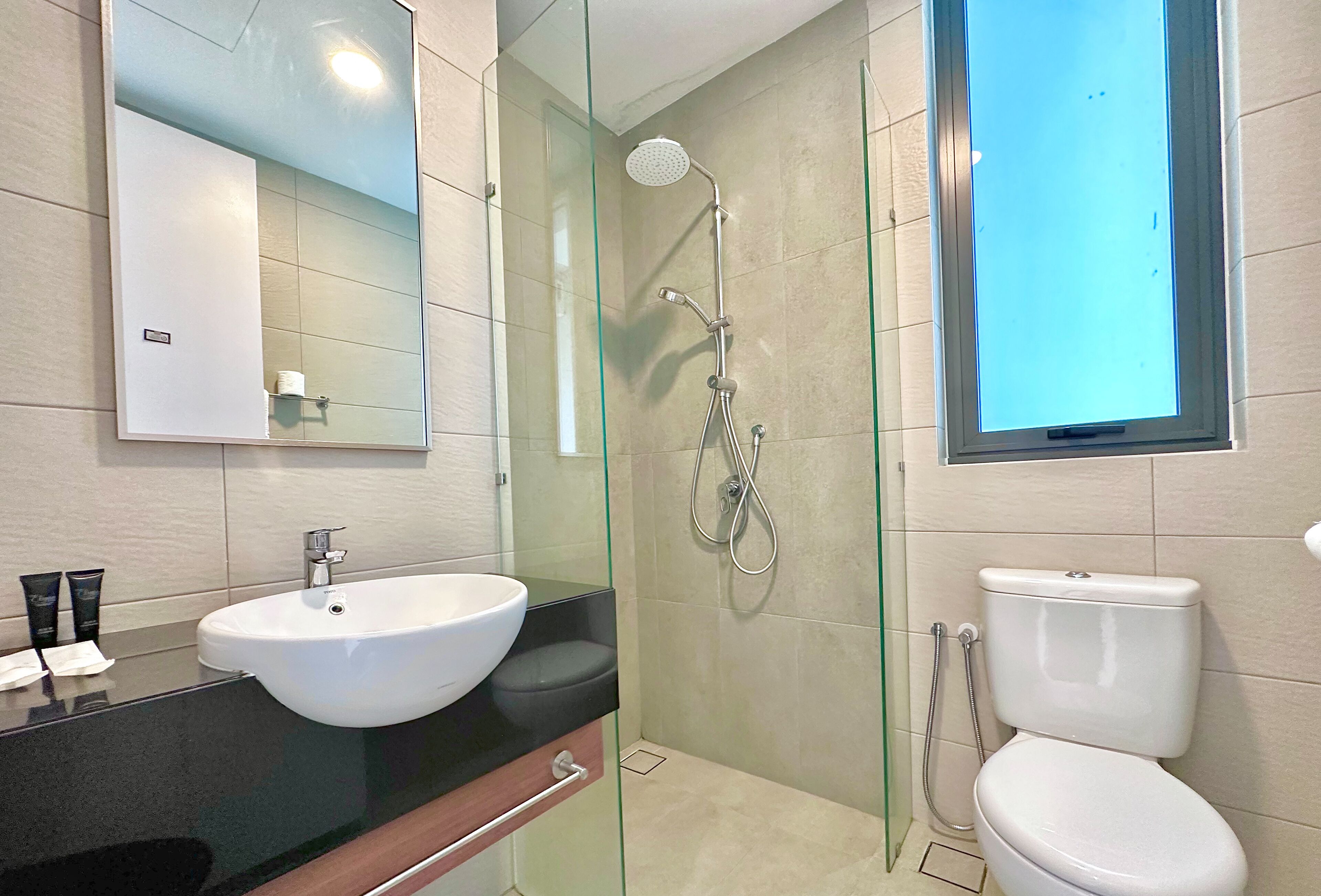 A modern bathroom with a glass-enclosed shower, a white sink, and a toilet.