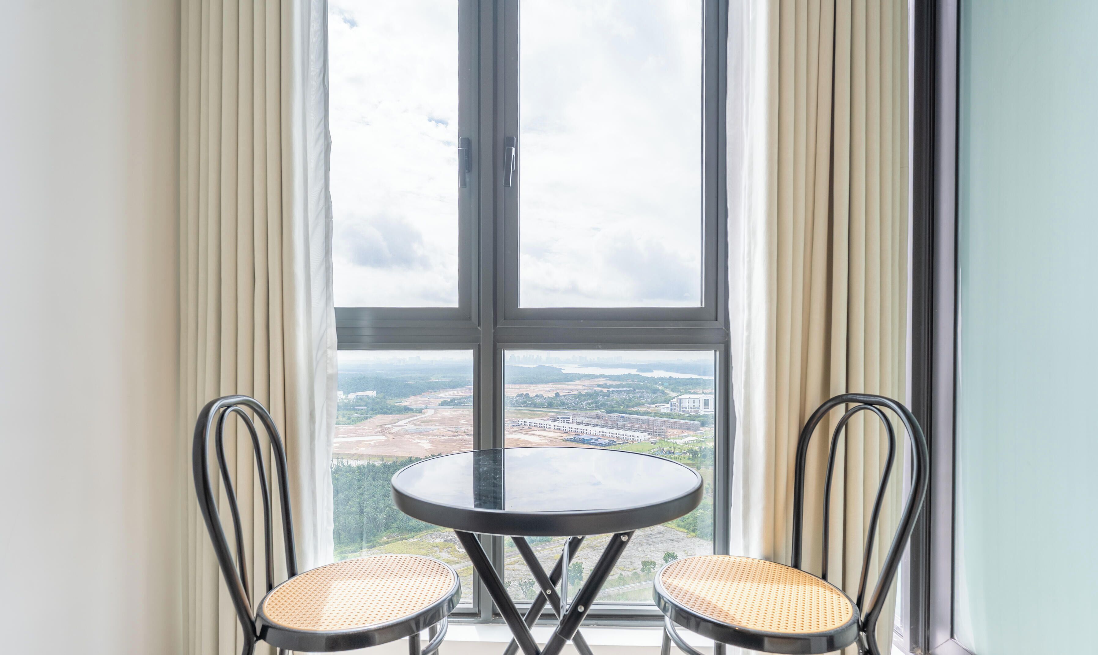 A room with a large window, two chairs, and a small round table.