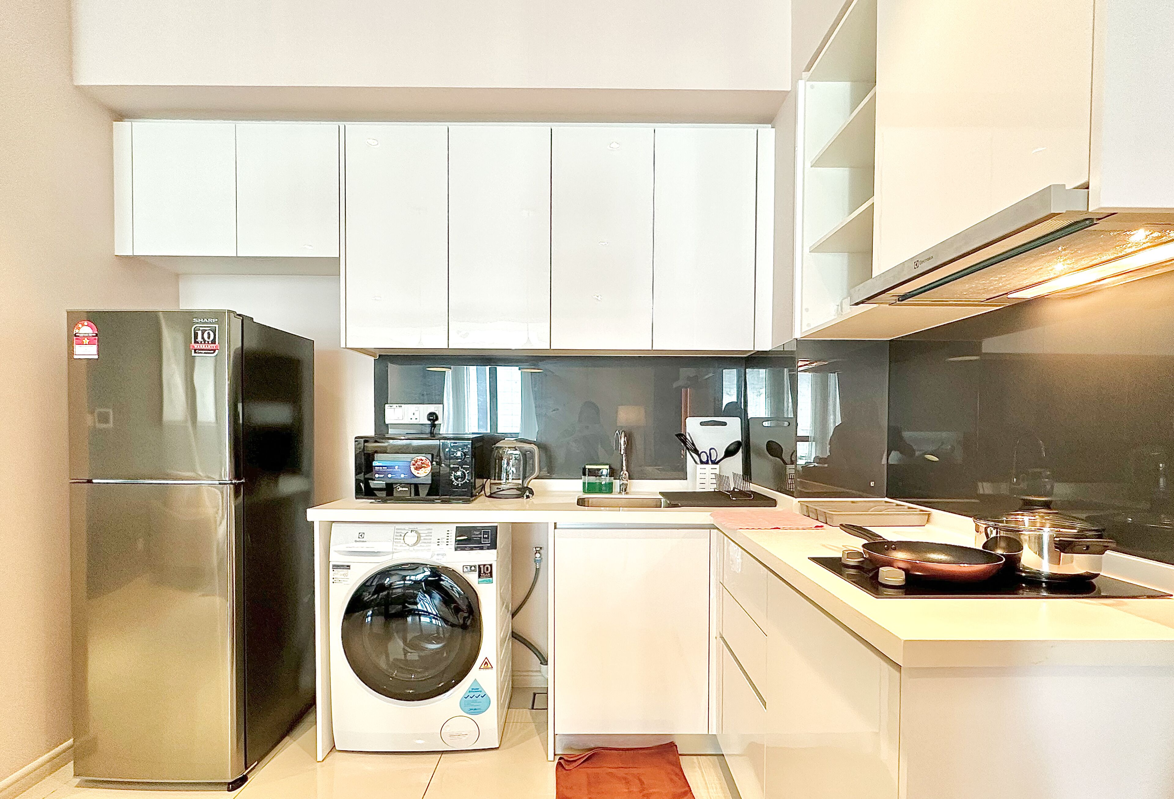 Een kleine keuken met een koelkast, wasmachine en fornuis.