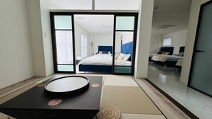 A modern hotel room with a large bed, a small table, and a sliding door leading to another room. - Luxury Hills1500 ㎡ Superb view patio Sauna BBQ 4 parking spaces, swimming pool, pets, near Fukuoka Airport (Kanenokuma, Hakata-ku, Fukuoka City)