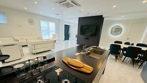 A modern kitchen with a central island, a dining area with chairs, and a living space with a sofa. - Luxury Hills1500 ㎡ Superb view patio Sauna BBQ 4 parking spaces, swimming pool, pets, near Fukuoka Airport (Kanenokuma, Hakata-ku, Fukuoka City)