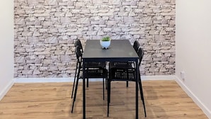Een eetgedeelte met een stenen muur, een tafel met stoelen en een potplant.